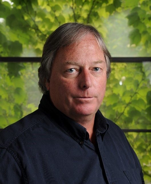 A headshot of Steven Geary against a green background.