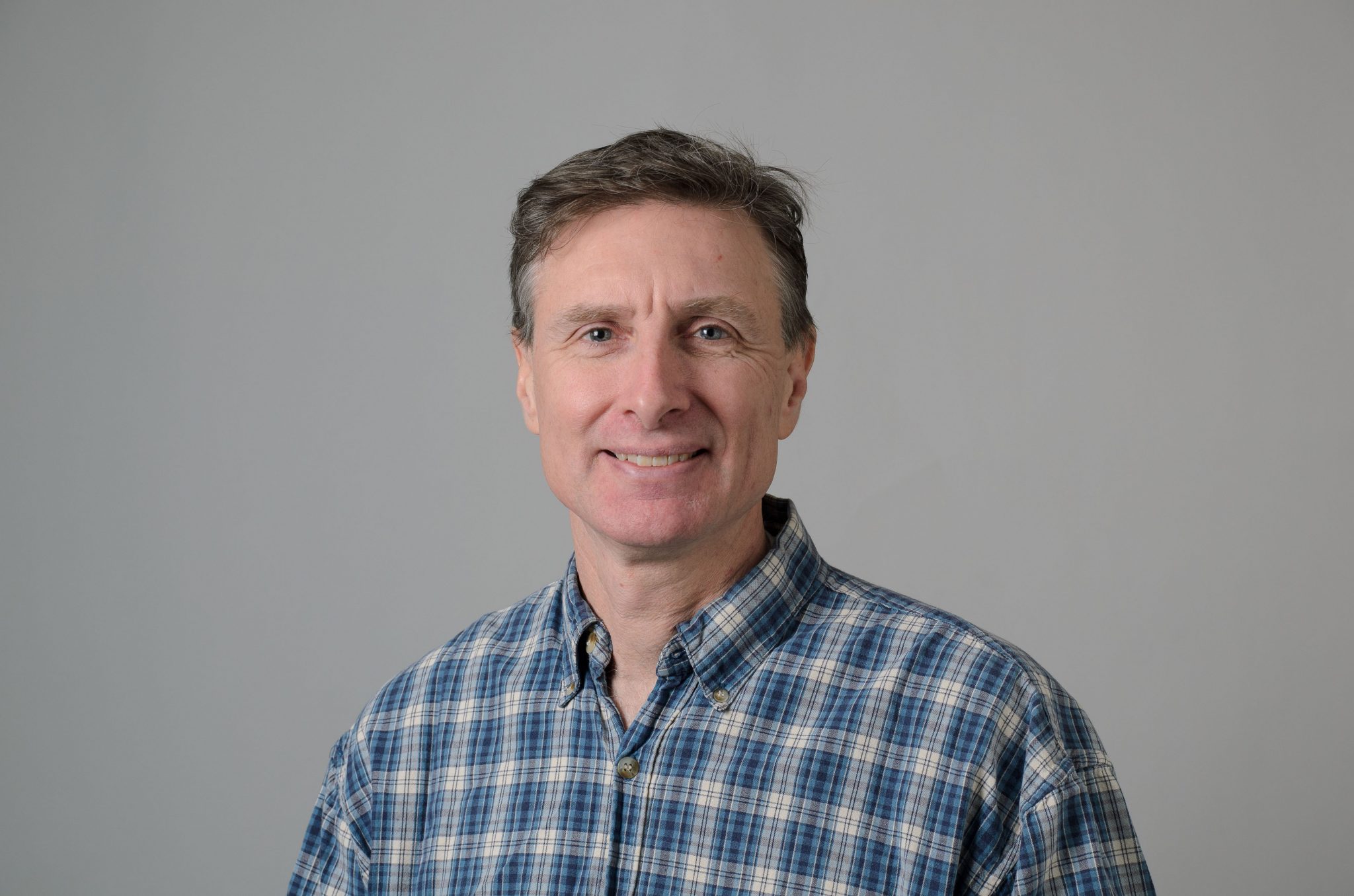 A headshot of Edan Tulman against a gray background.